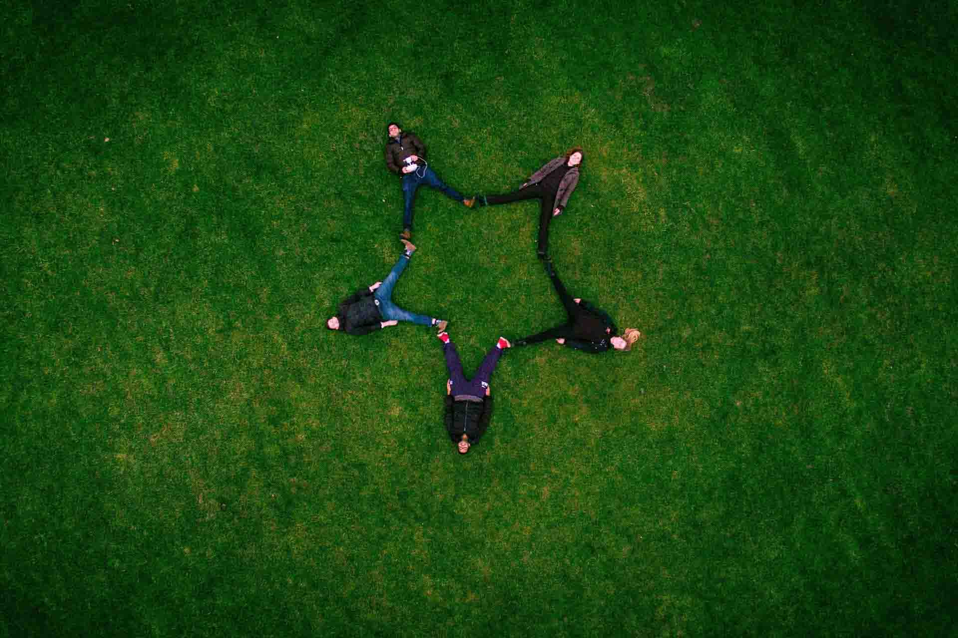 A group of people lying on the grass in a star shape