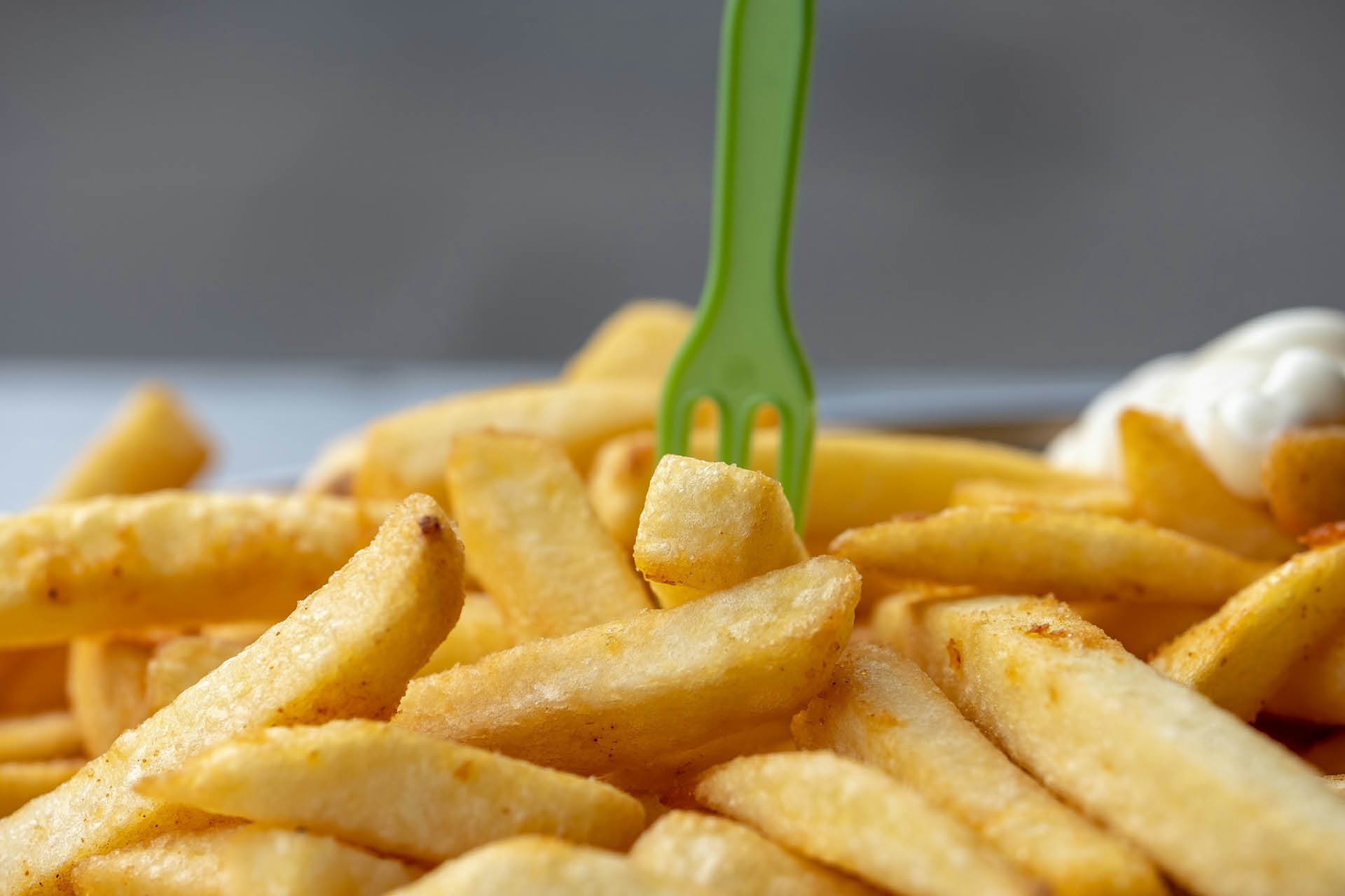 A pile of chips with a plastic fork stuck in a chip.