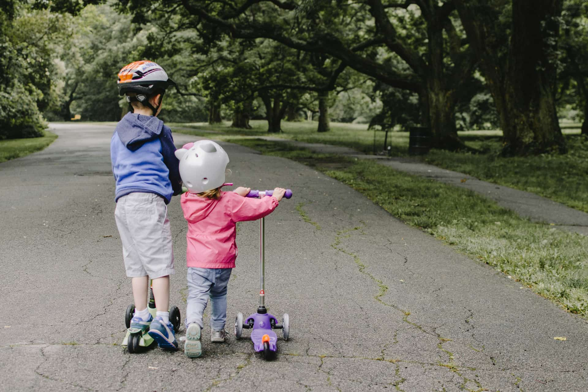 Two children playing on a scooter.