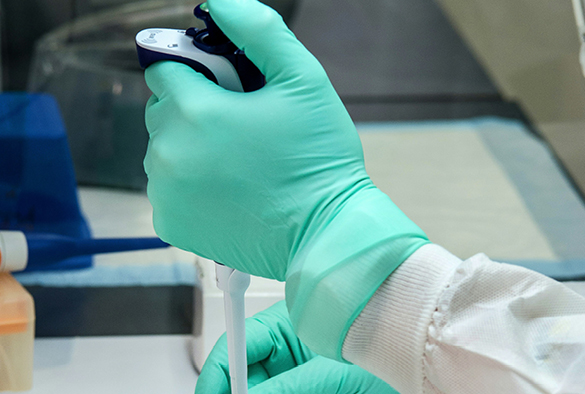 Scientist wearing latex gloves with a microscope.