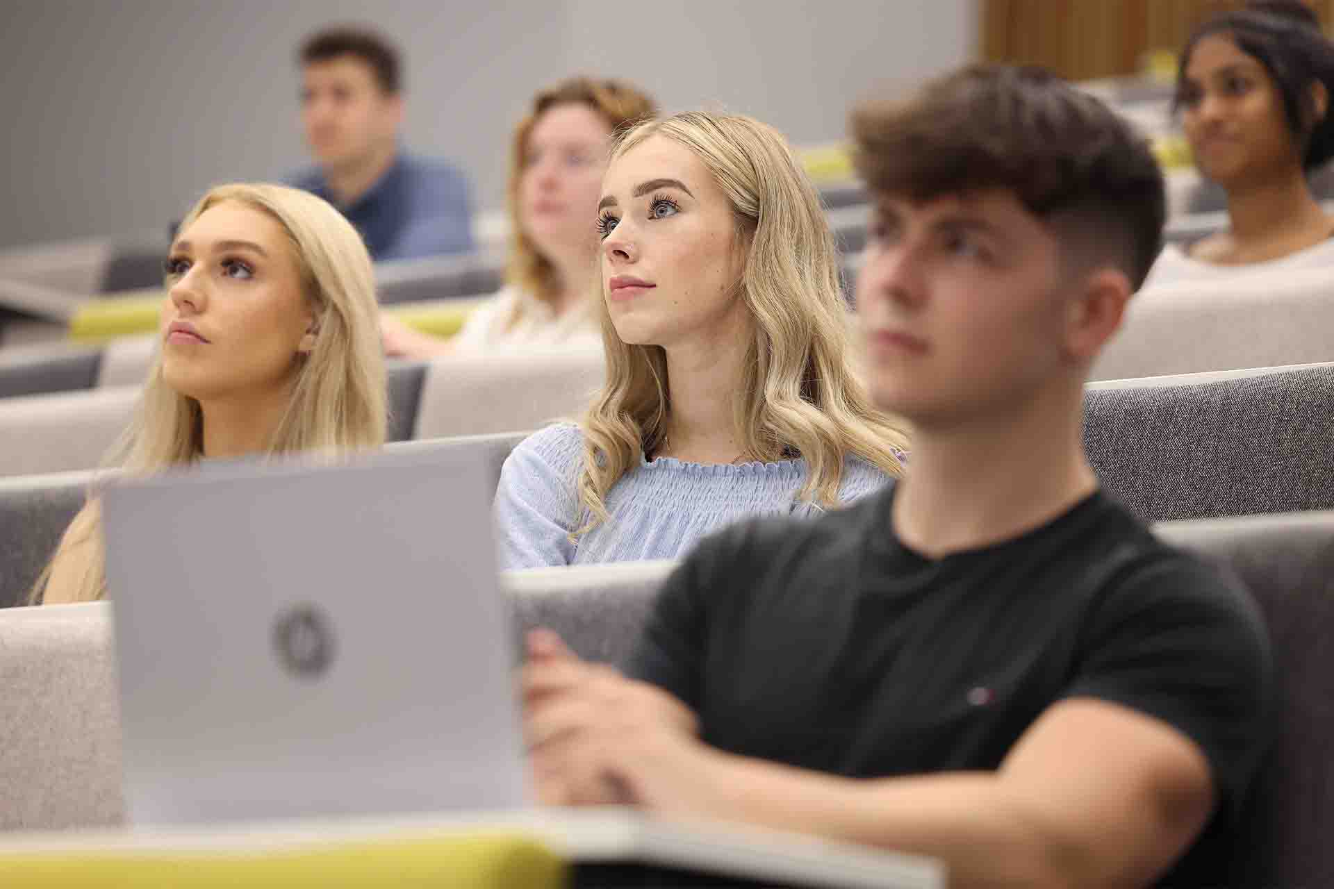 Students in a lecture theatre on their laptops.