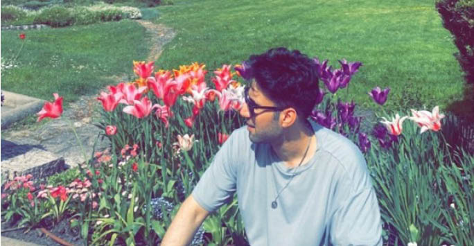 Ammar sat in front of flowers.