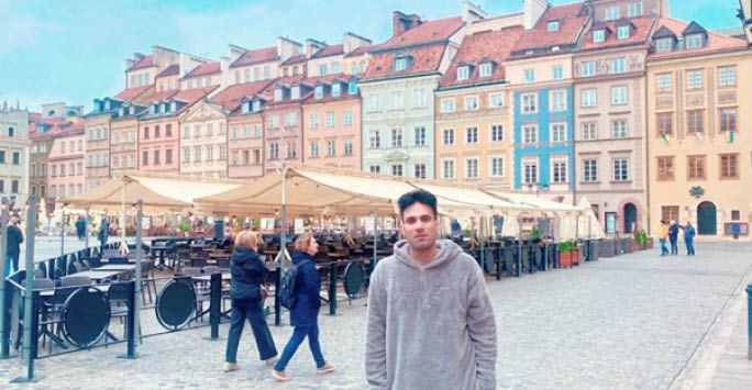 Ammar in front of buildings in Warsaw.