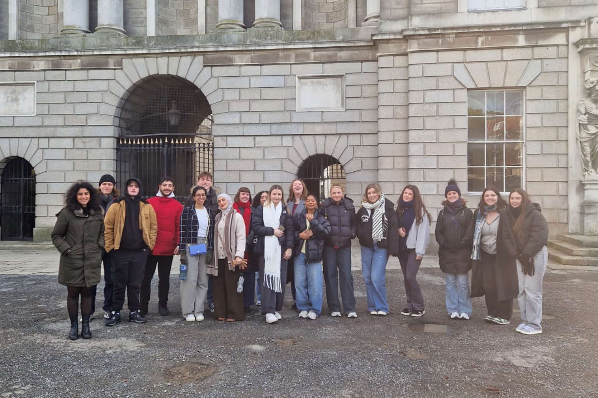 A large group of students stood outside a large brick building.