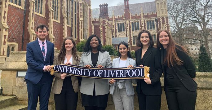 The University of Liverpool Moot Team stood together outside of Lincolns Inn, London. They are holidng a scarf that reads The University of Liverpool