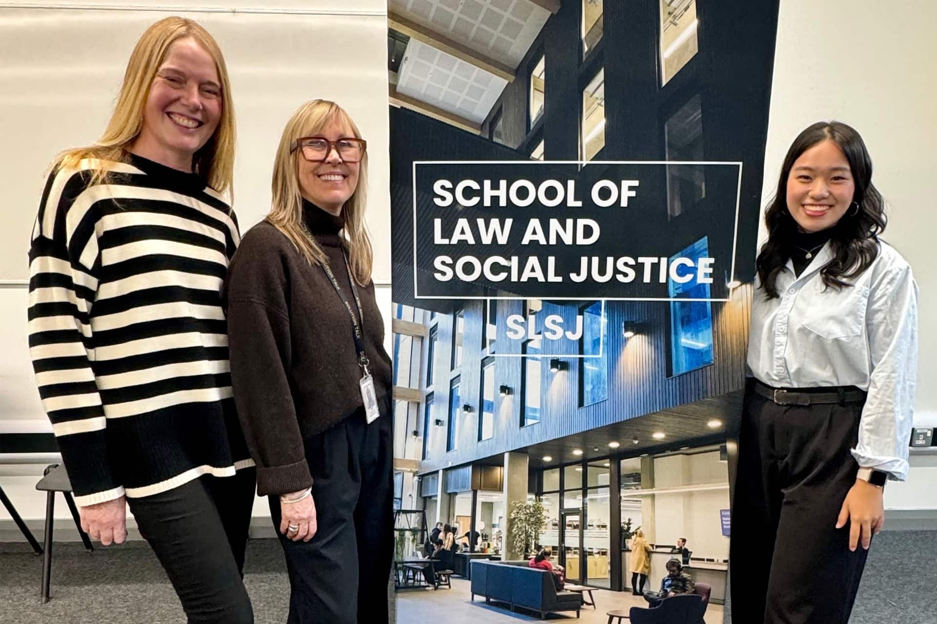 Mediation workshop hosts Julie and Laura, stand with student Angeline next to a banner that reads 