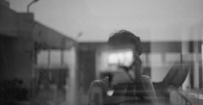 Black and white image of a person taking a photo in a mirror - blurred.
