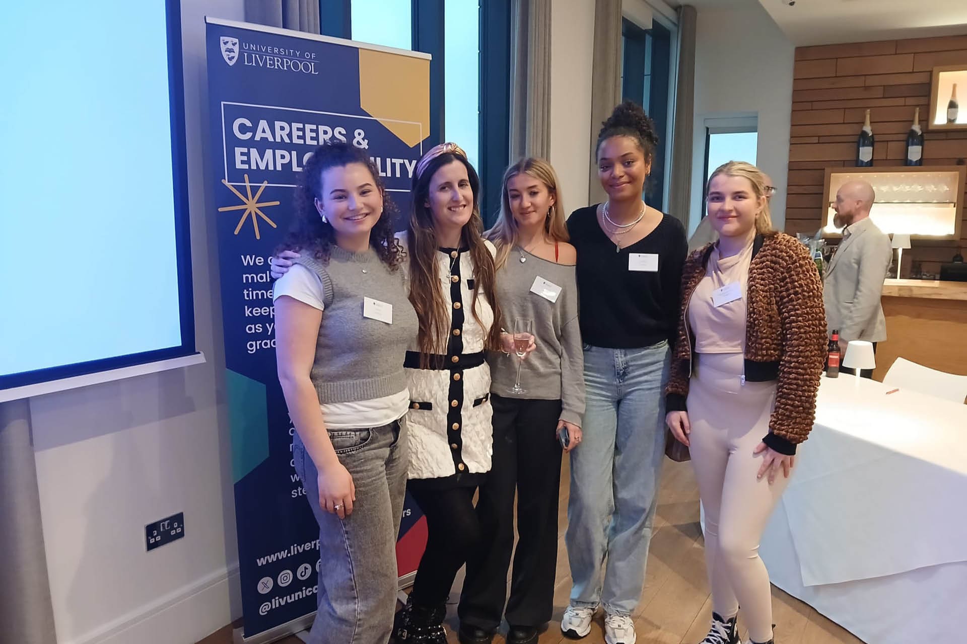 Students taking a group photo in front of an event banner.