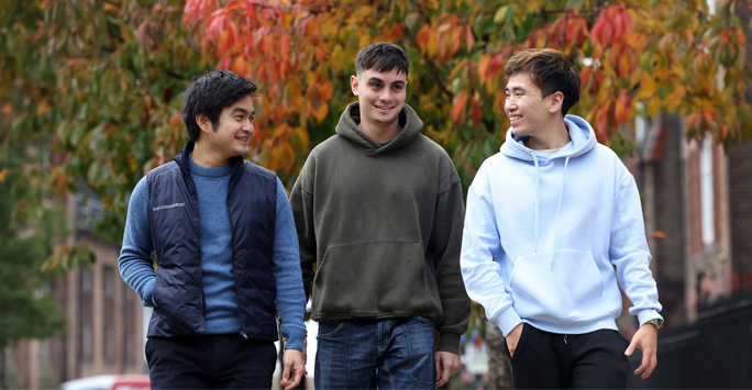 Three students walking together through campus.