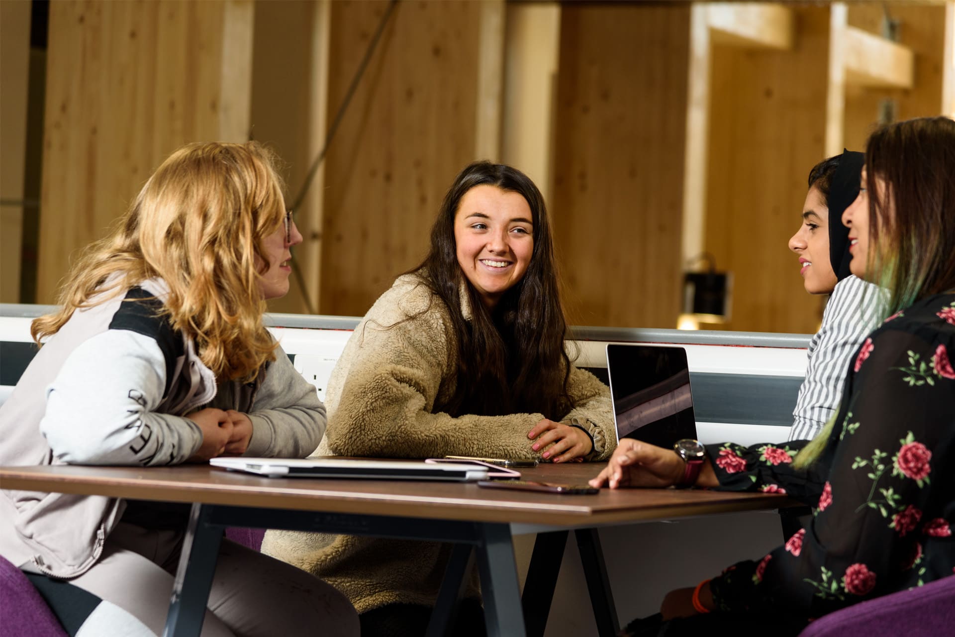 Four students sit around a table, engaging in conversation.