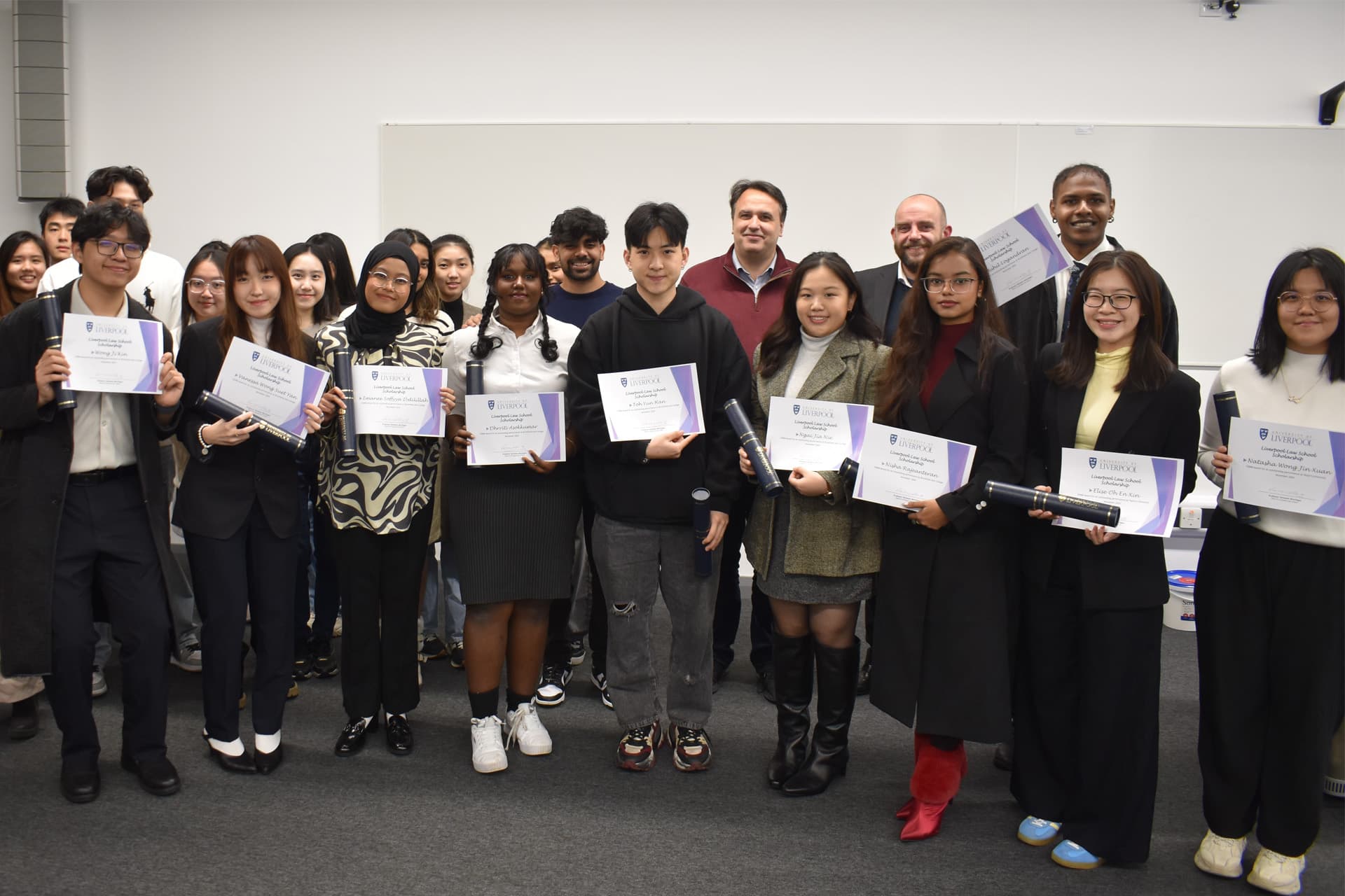 A group of students stand together with the Dean and Head of the Liverpool Law School. Some of the students are holding certificates.