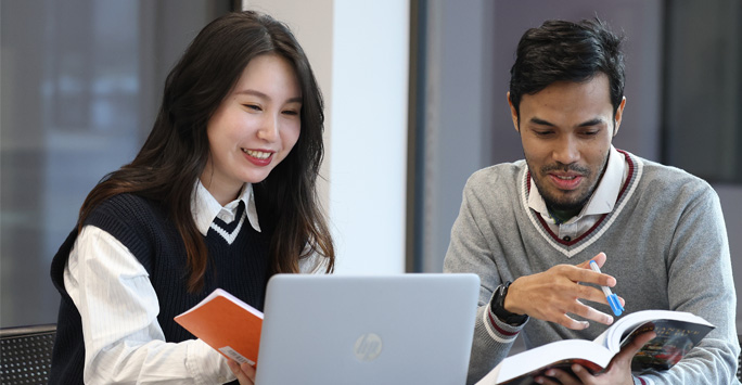 Two students study together at a desk.