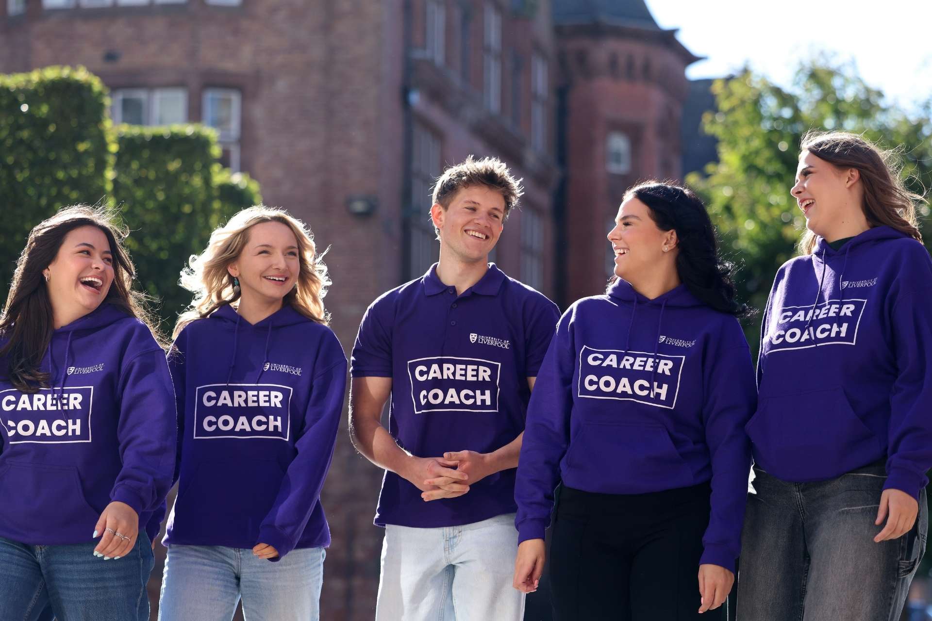 A group of people wearing matching purple T-shirts and hoodies with