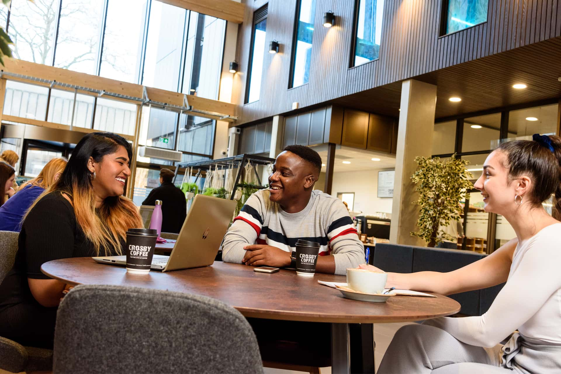 Students sit around a table, smiling and engaged conversation.