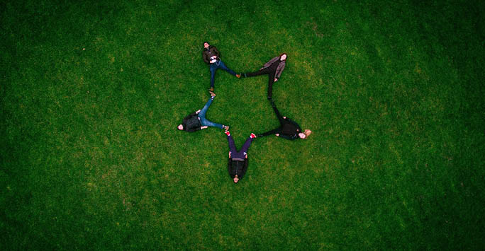 5 people lying on the grass in a star shape.
