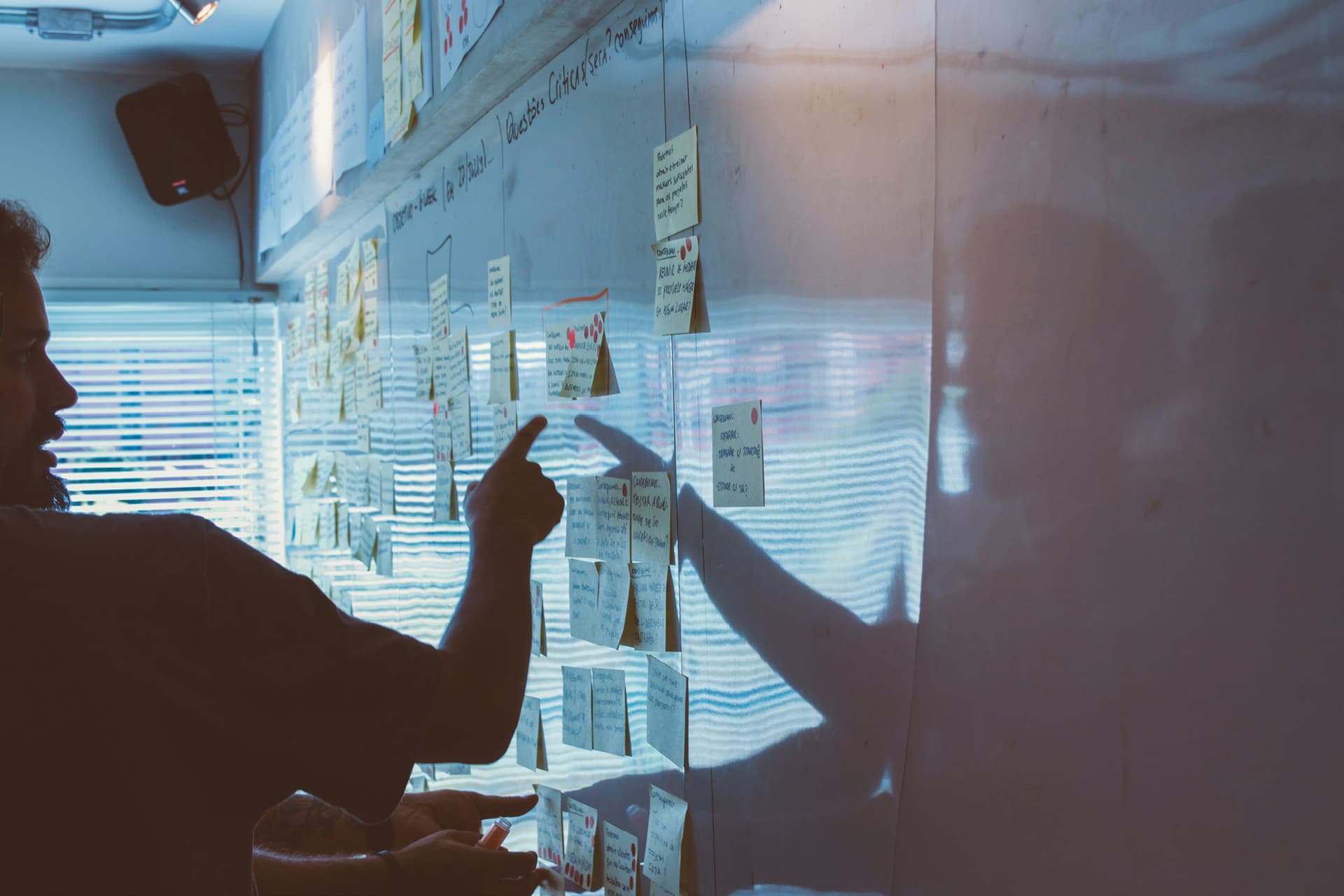 Person pointing to post it notes on a whiteboard.