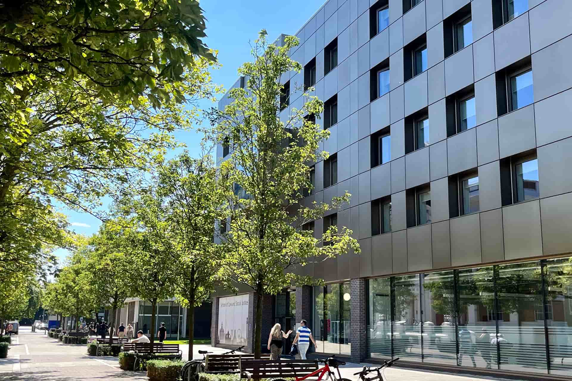 The exterior of the Law Clinic Building, featuring a bronze-coloured facade, on a sunny day.