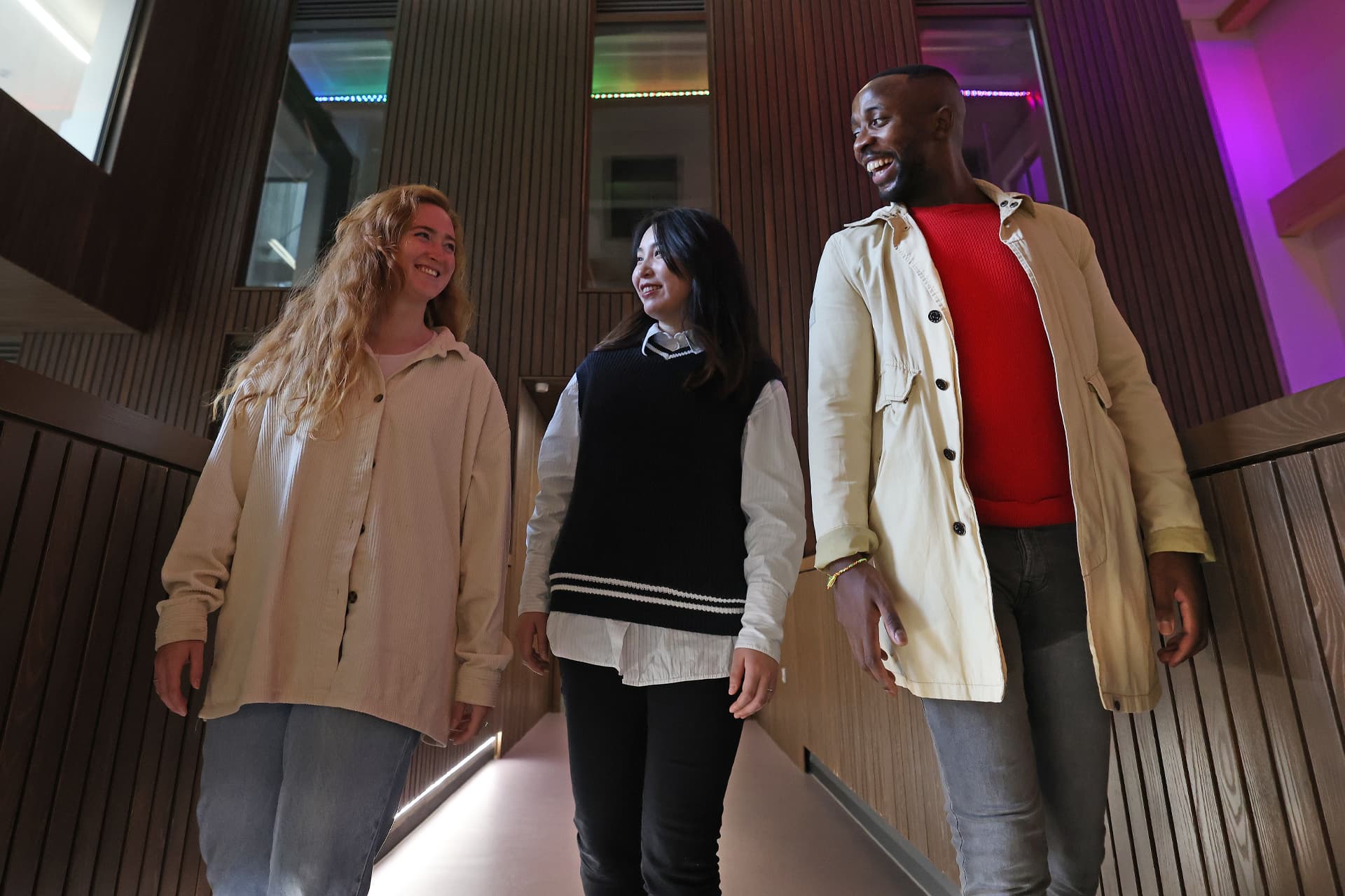 Three students walk together inside the School of Law and Social Justice building.