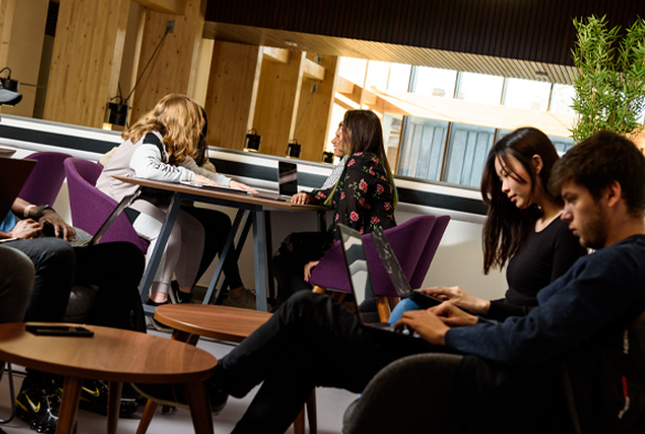 A group of students sit on couches and tables in the School of Law and Social Justice.