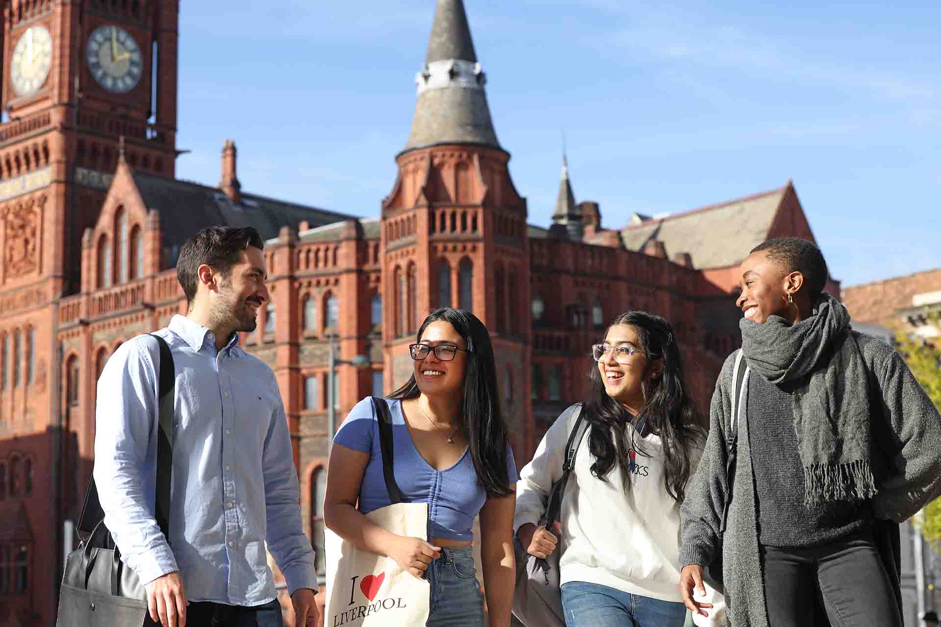 Four students walking and talking outside the Redbrick building.