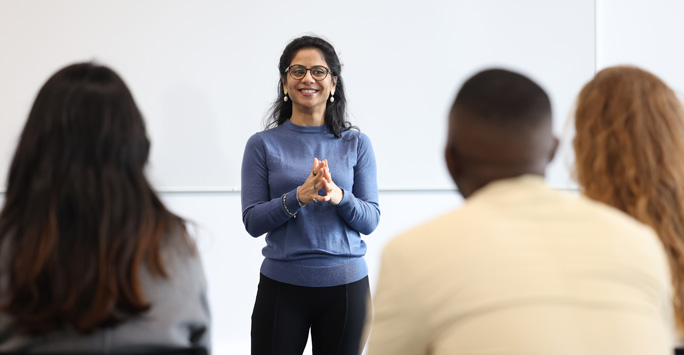 A speaker stands facing the room of people.