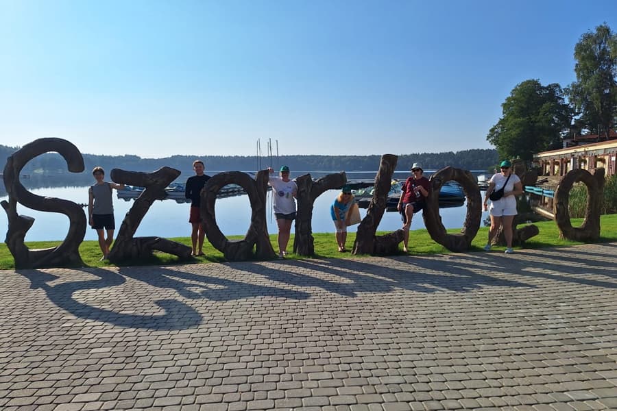 Attendees of the summer school at the Szarlota sign at edge of the lake