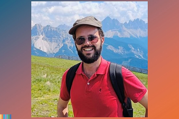 A person posing for a photo with mountains in the background.