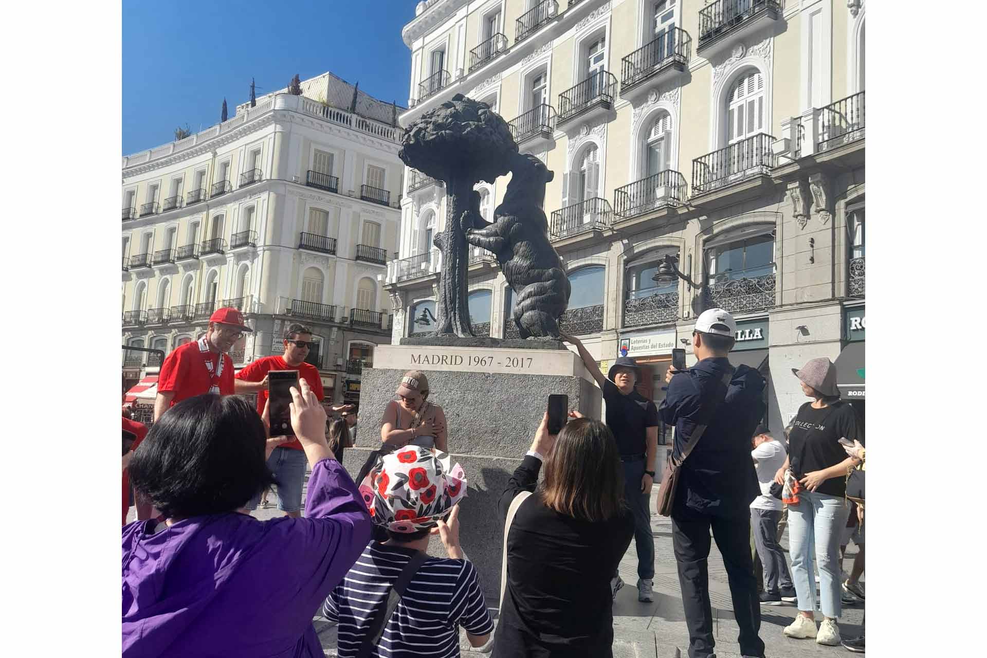 Tourists in a city centre next to a bear statue