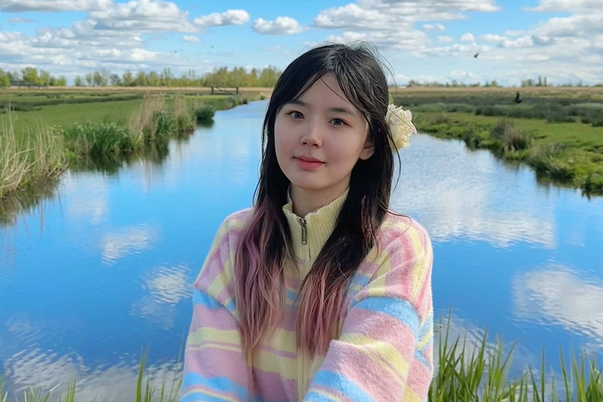 A chinese student sitting in the English countryside smiling