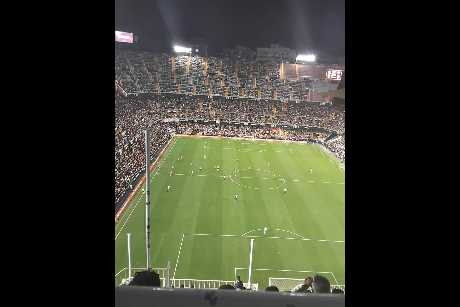 A view from a seat in a football stadium with a green football pitch in the distance