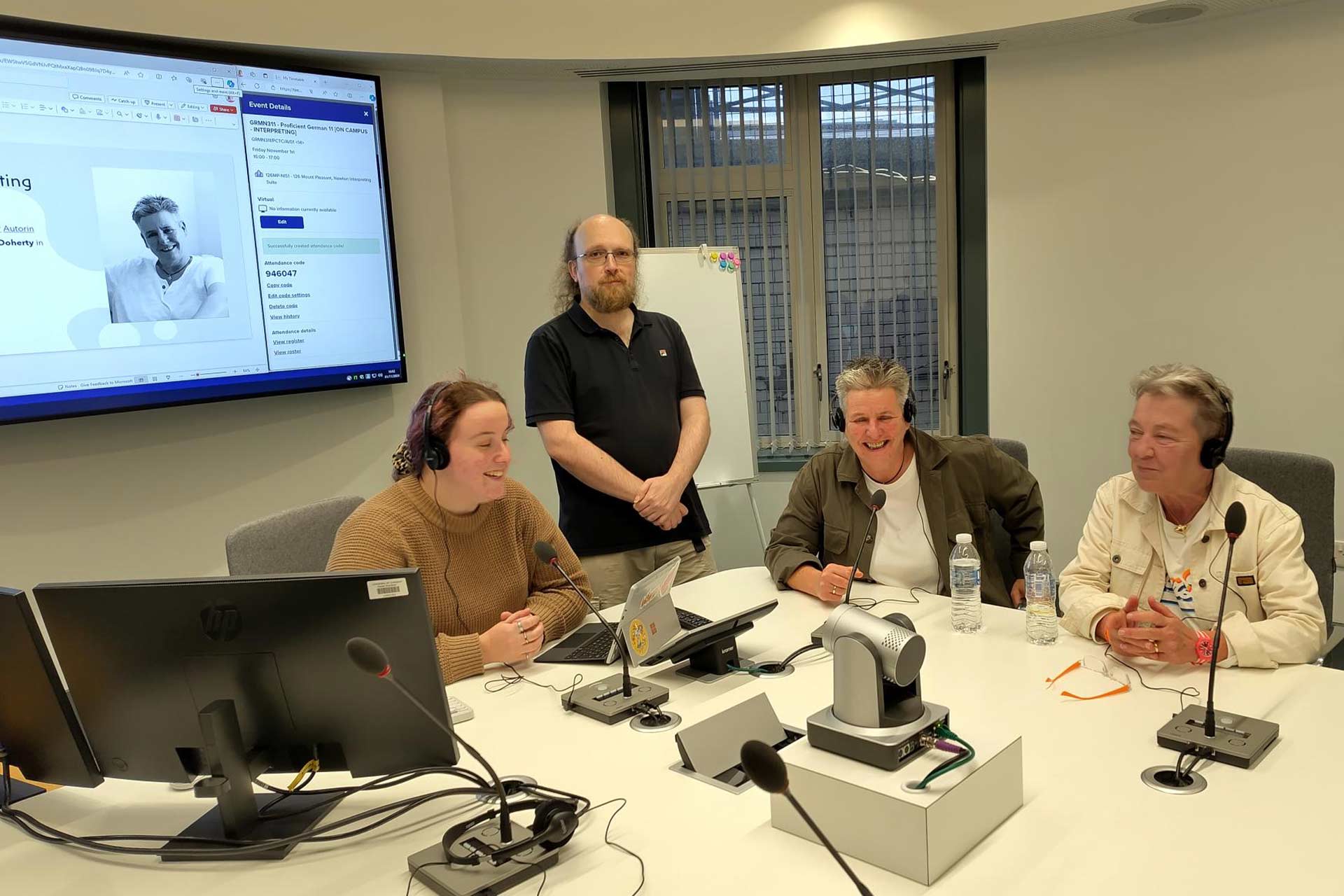 Three people sitting at a table wearing headphones smiling and talking