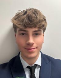 Headshot of a young male student wearing a suit against a white wall