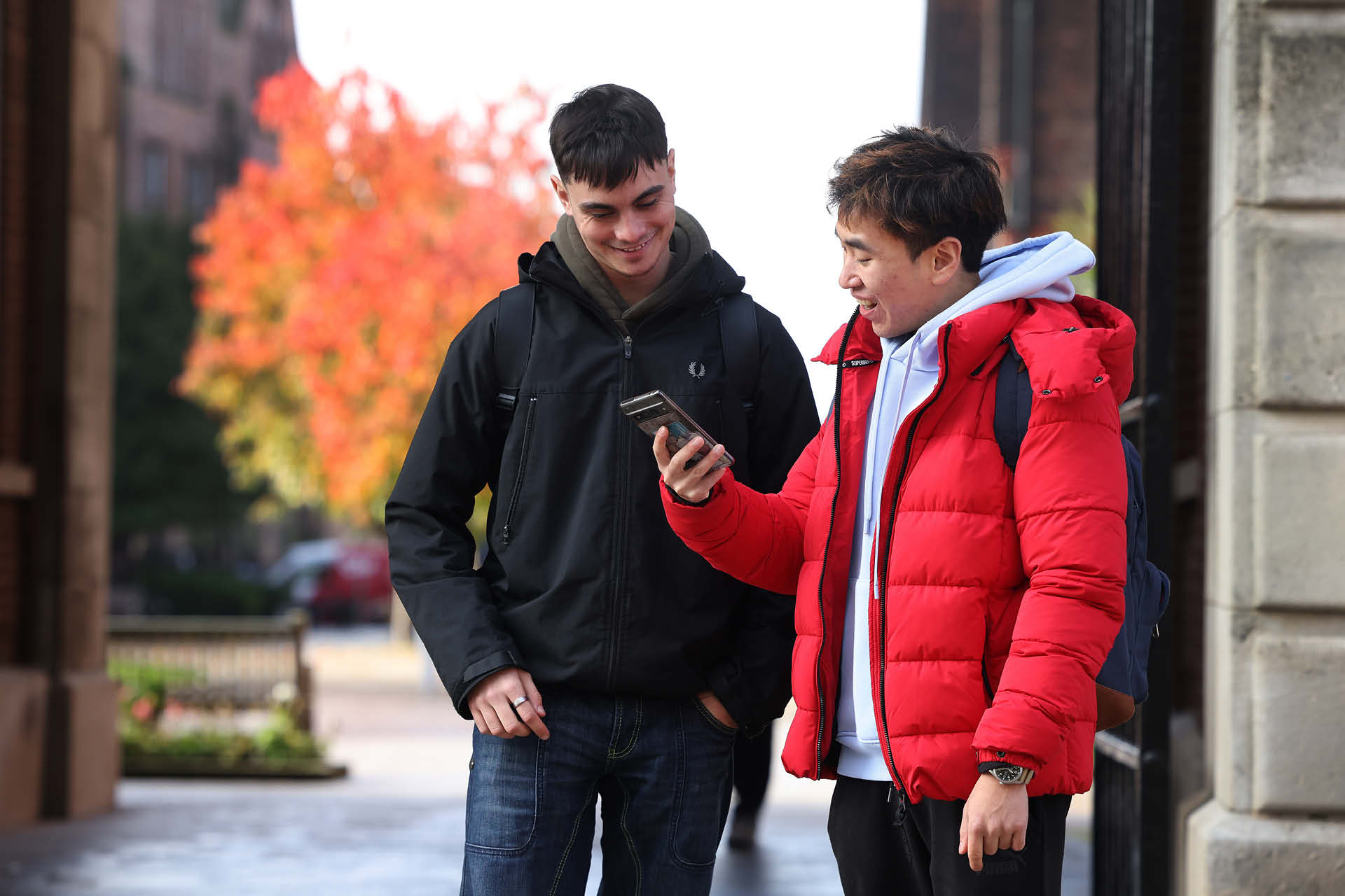 Two students looking at a phone and smiling