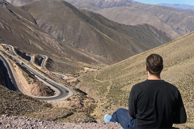 Student sat on a hill looking down at an Argentinian landscape