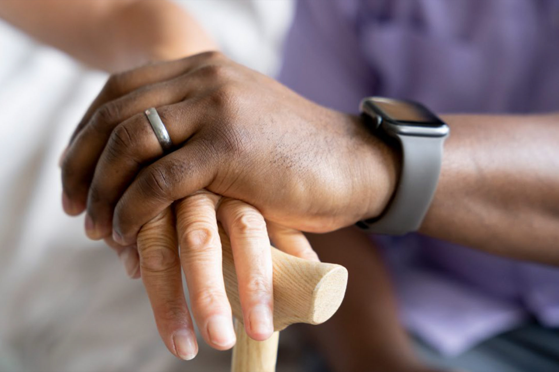 A person resting their hands on a walking stick