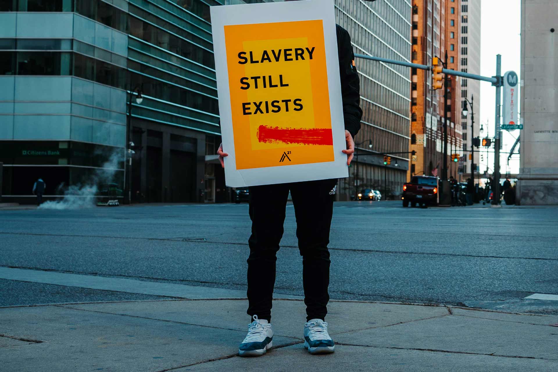 Man holding sign with text that reads 'slavery still exists'