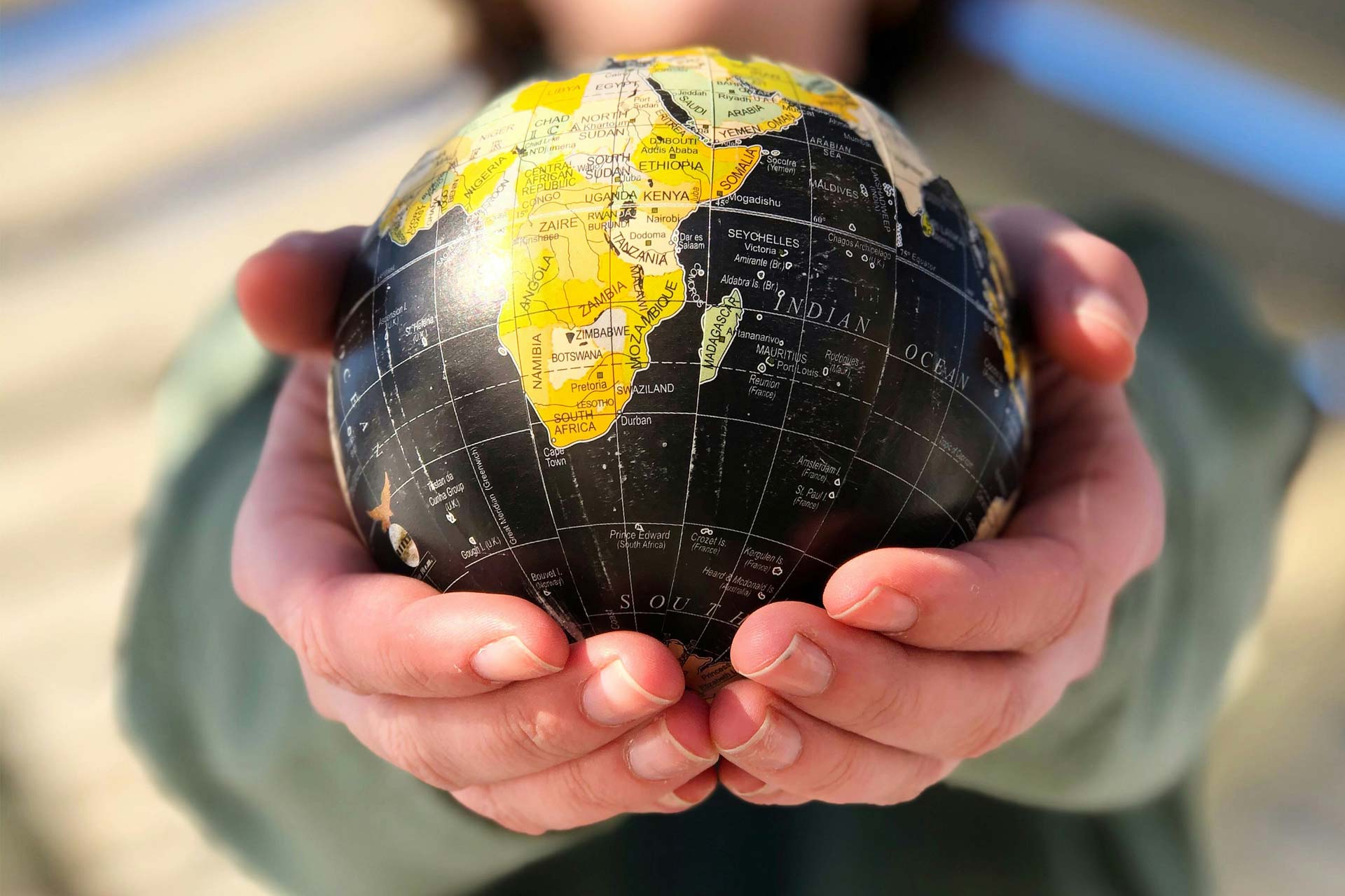 Person holding a small globe in their hands