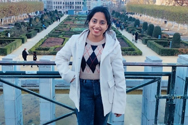 A person standing on a railing in front of a garden.