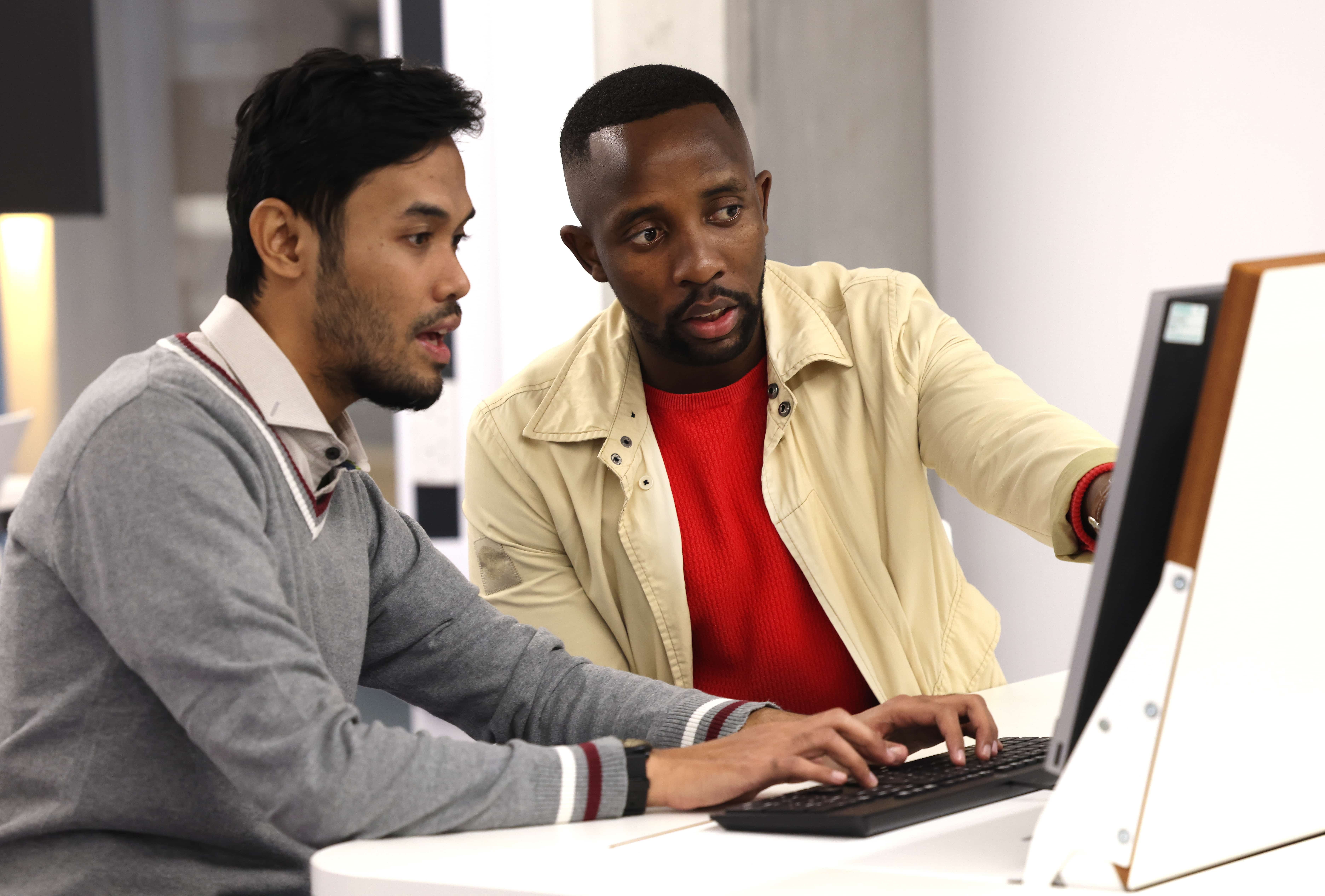 Two students on campus, working together at a computer.