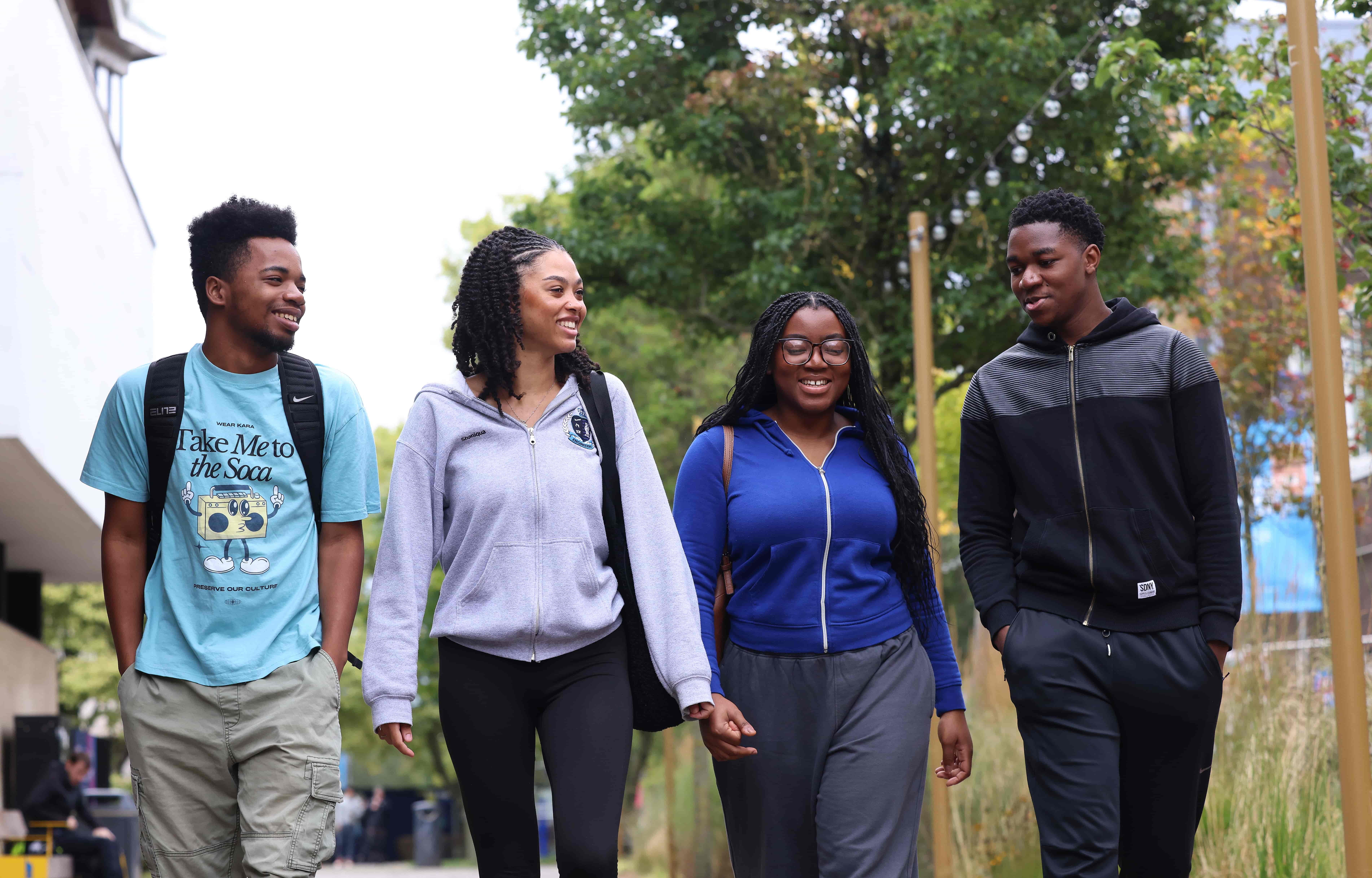 A group of four students walking across campus while engaged in conversation.