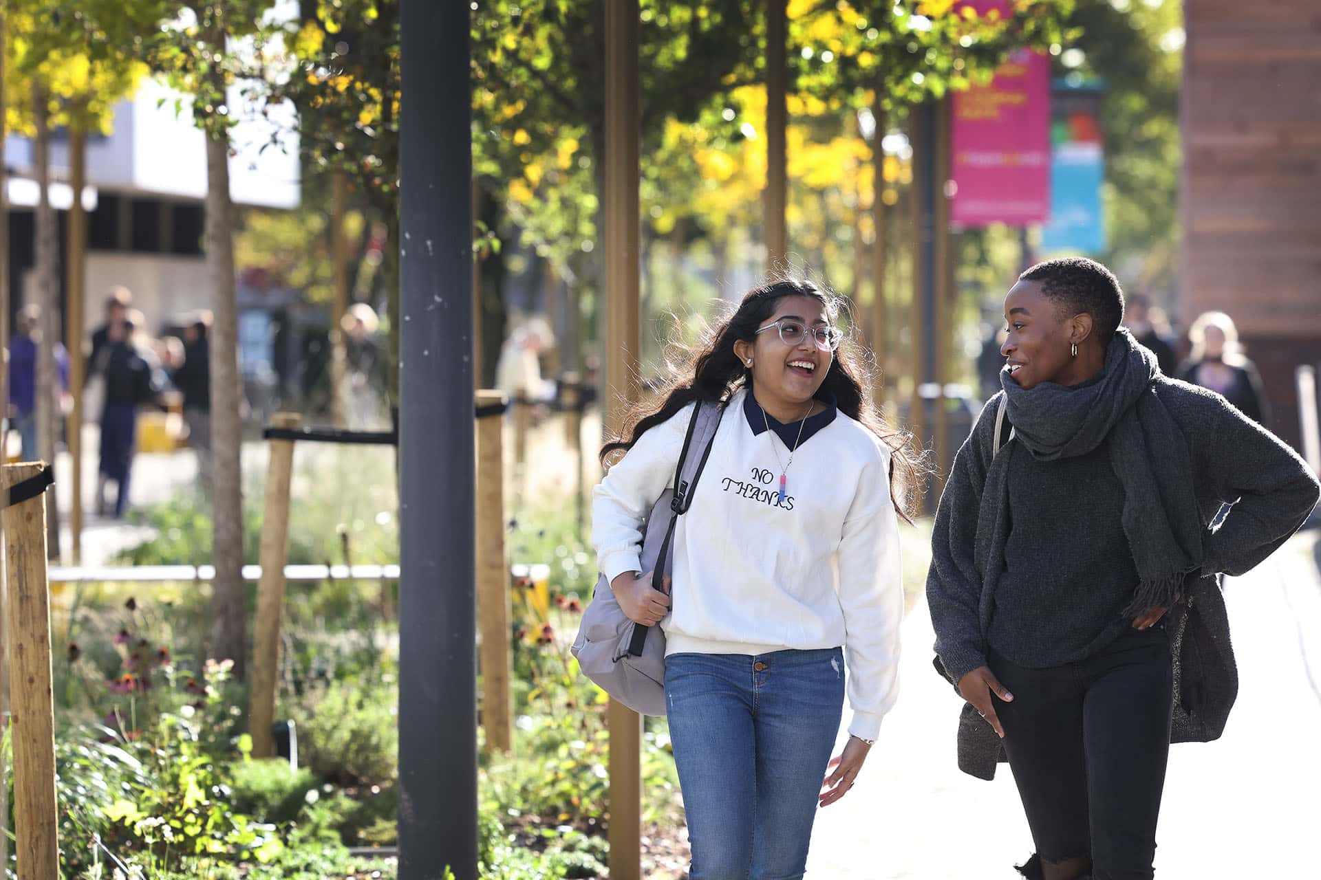 Two students walking through campus laughing