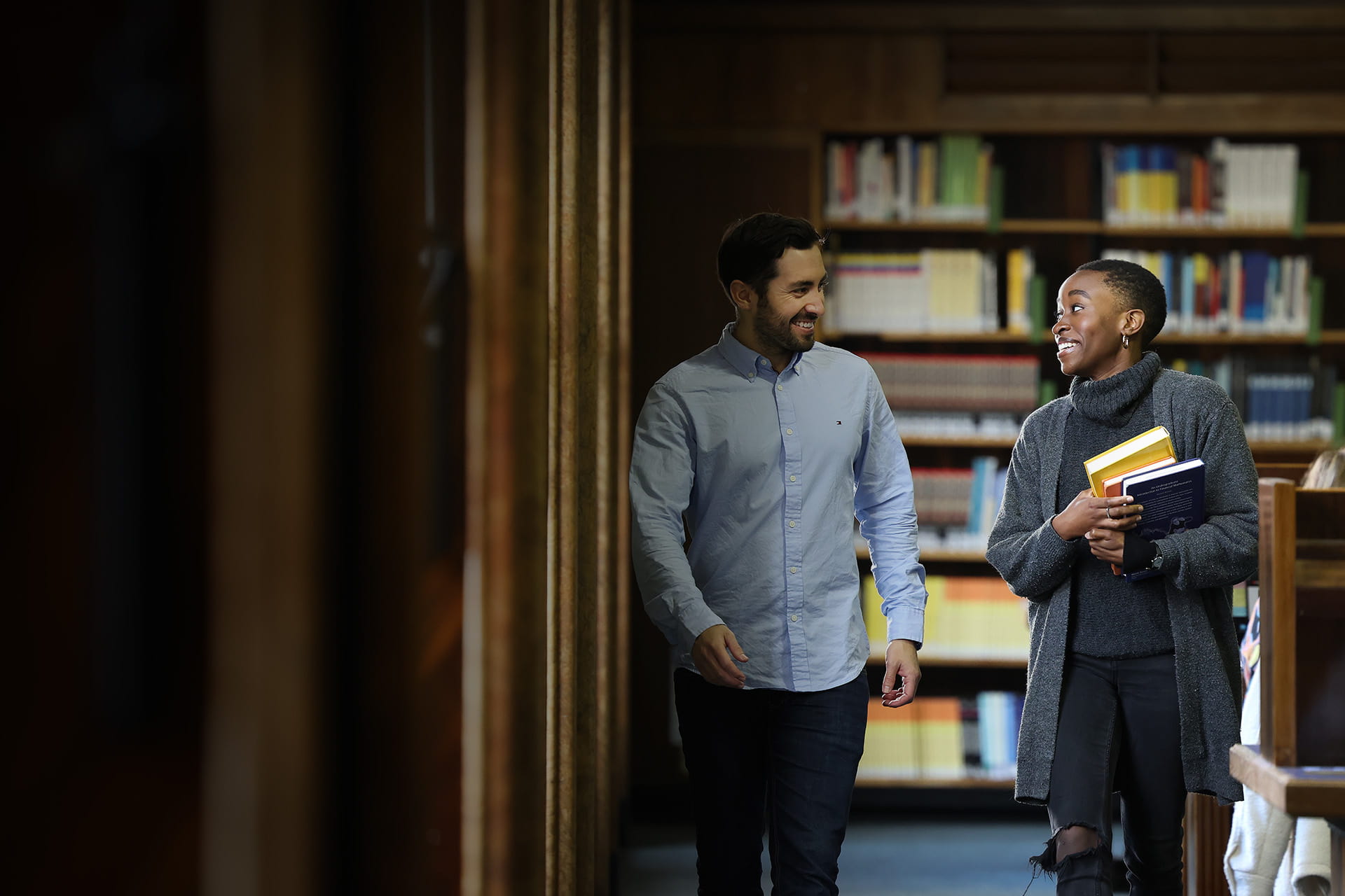 Two students talking and walking in the library