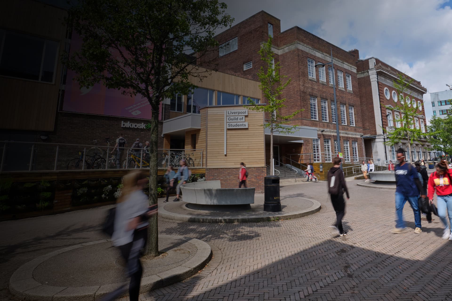 Students walking past a building with a sign that reads Liverpool Guild of Students.