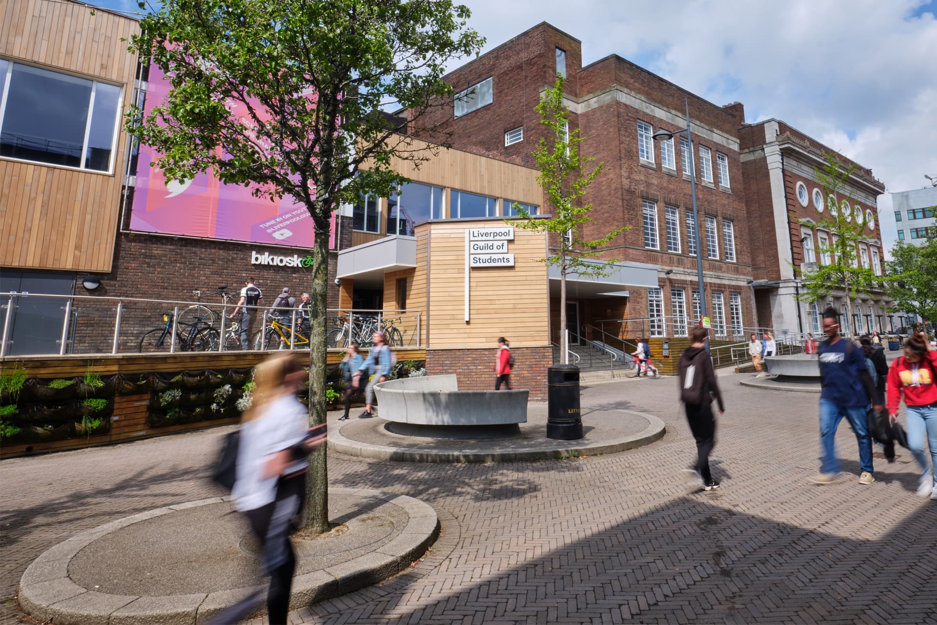 Students walking past a building with a sign that reads Liverpool Guild of Students.