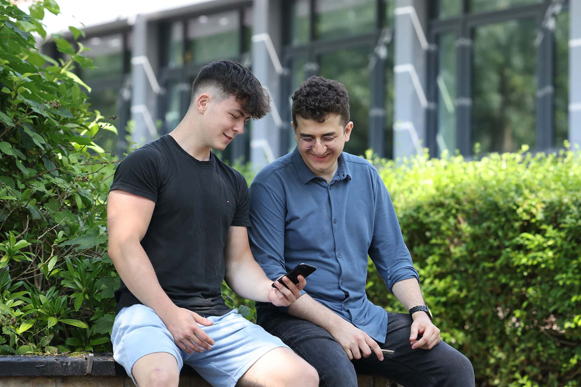 Two students sittnig down chatting looking at a phone