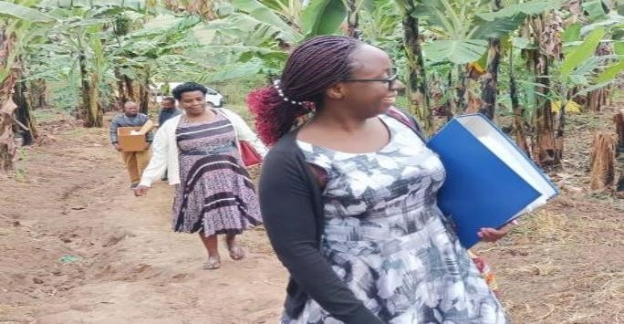 An image of two black women carrying folders and walking on a jungle path