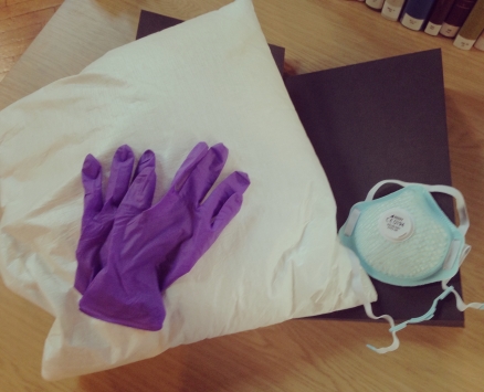 An image of a P60 mask and purple latex gloves on a pillow on top of a hardback blue book