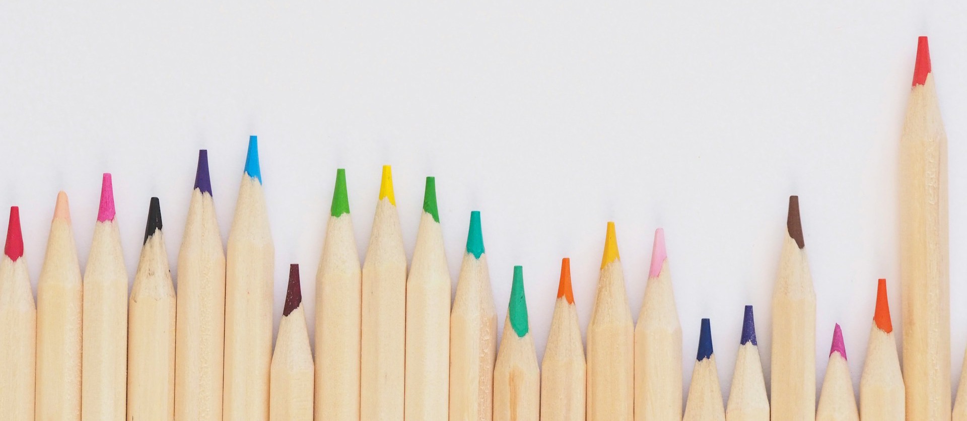 Colourful pencils lined up on top of a white surface