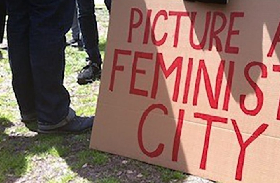 Feminist City Network sign by someone standing