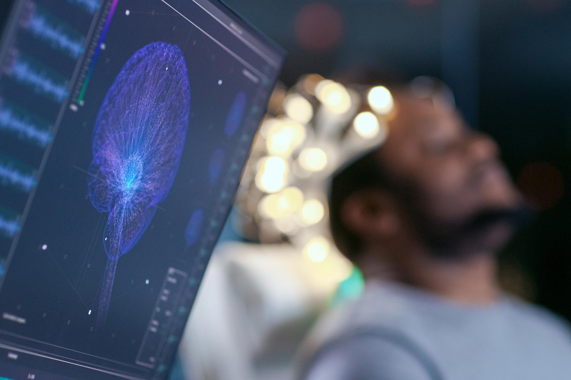 Monitors Show EEG Reading and Graphical Brain Model. In the Background Laboratory Man Wearing Brainwave Scanning Headset Sits in a Chair with Closed Eyes. In the Modern Brain Study Research Laboratory